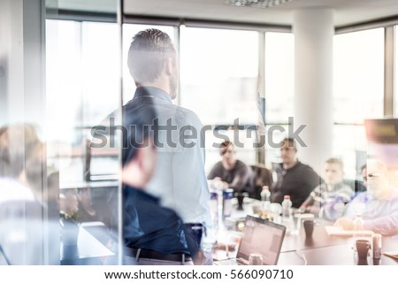 Business man making a presentation at office. Business executive delivering a presentation to his colleagues during meeting or in-house workshop. Rear view. Business and entrepreneurship.