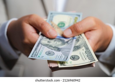 Business man and money in us dollar hold on hand wearing a brown suit jacket and Give to me USD, Pay, exchange money vietnamese on white background.
