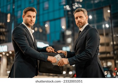 Business man in night Ney York. Planning of two business teams strategy. Business men giving money. Businessman offering money for collage on night city. Offering money for business. - Powered by Shutterstock