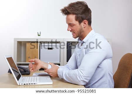 Business man in office with RSI syndrome holding his aching hand