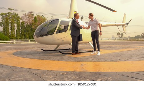 Business Man And Pilot Talking Near Small Private Helicopter On A Landing Point