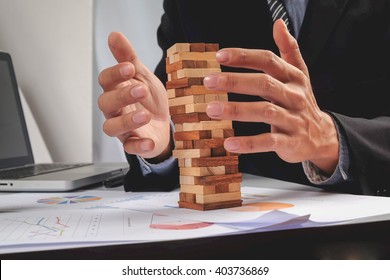 business man placing wooden block on a tower concept risk control, Planning and strategy in business - Powered by Shutterstock