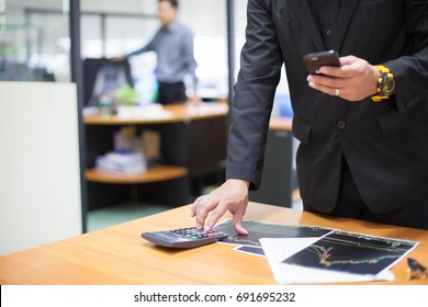 Business man pointing stock market document  use smartphone and calculator with doing finance at his office.