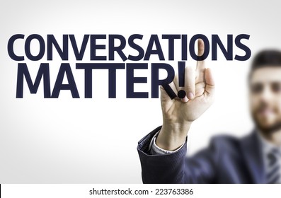 Business man pointing to transparent board with text: Conversations Matter