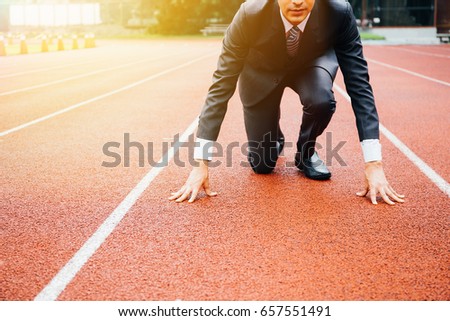Business man preparing to run on the competition running track