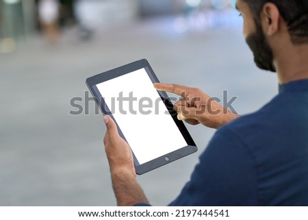 Business man professional holding digital tablet in hands using pad with white empty screen mock up template outdoors on urban city street. Mockup display for ads. Over shoulder view