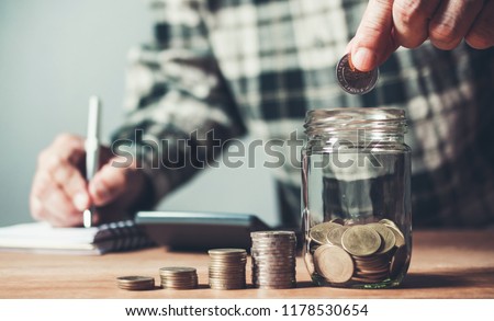 Business man putting coin in glass bottle saving bank and account for his money all in finance accounting concept.