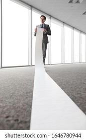 Business Man Reading A Long Paper Band Roll In Office