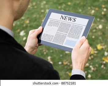 Business Man Reading News On Digital Tablet At Park.