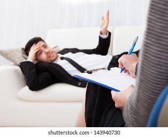 Business Man Reclining Comfortably On A Couch Talking To His Psychiatrist Explaining Something