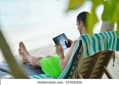 Business Man Relaxing And Use Tablet Computer At Beautiful Tropical Beach