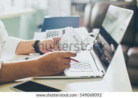 Business man review his resume on his desk, laptop computer, calculator and cup of coffee,Seleted focus.
