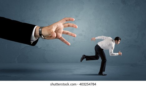 Business man running away from a huge hand concept on background