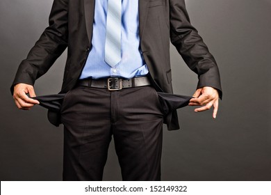 Business man showing his empty pockets  on gray background - Powered by Shutterstock