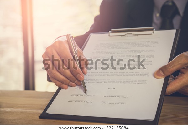 Business man signing a contract. Owns the\
business sign personally, director of the company, solicitor. Real\
estate agent holding house, financial or renting property, merger\
and acquisition\
concept.