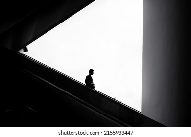 Business man in silhouette going down escalator. Black and white photography concept