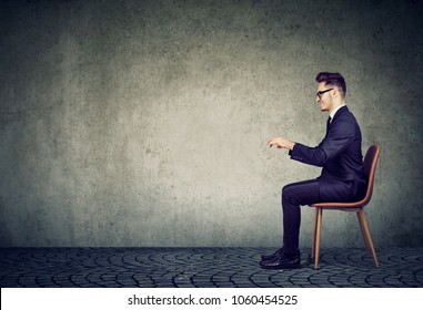 Business man sitting at invisible table pretending to type on computer