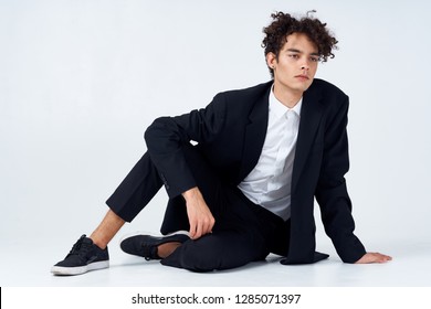 Business Man Sitting On The Floor In A Dark Suit, Leaning On His Arm