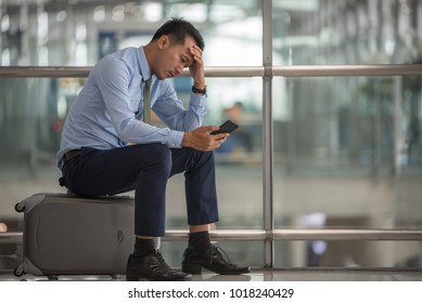 Business man sitting at the terminal airport, left hand touch at head, headache,right hand holding smarat phone,waiting traveling,flight delay ,selective focus,traveling concept, copyspace