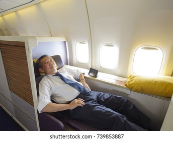 Business Man Sleeping At The First Class Of Airplane In Comfortable Single Seat.