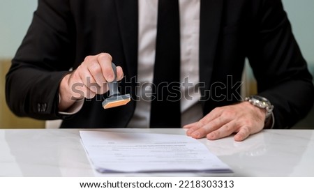 Business Man Stamping With Approved Stamp On Document. Business approve Stamp and certificate concept. Businessman Hands Stamping a document
