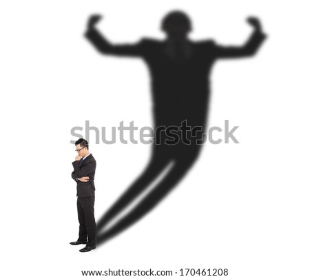 Business man standing and casting shadow of a strong man 