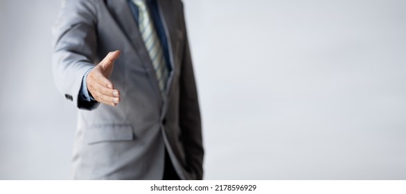 A Business Man In A Suit Extends His Hand Forward As A Business Handshake, A Universal Handshake Is A Formal Salute And Appreciation Of Business Dealings. Business Handshake Concept.