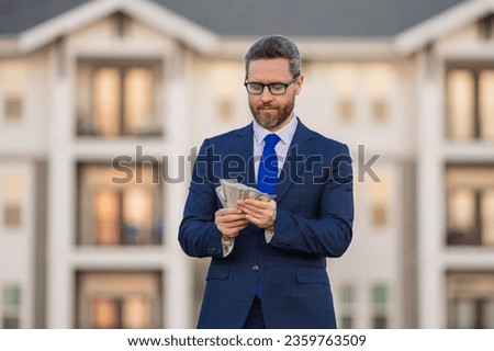 Business man in suit holding cash money in dollar banknotes outdoor. Portrait of business man with bunch of dollar. Dollar money concept. Career wealth business. Insurance agent. Success business.