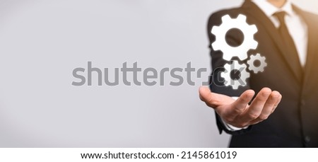 Business man in suit holding metal gears and cogwheels mechanism representing interaction teamwork concept,hand hold group of virtual cog gears wheel.