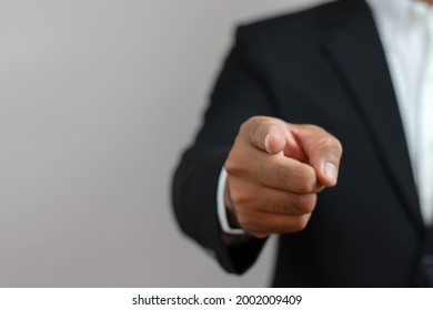 A business man in a suit is using his index finger to give a command or order.