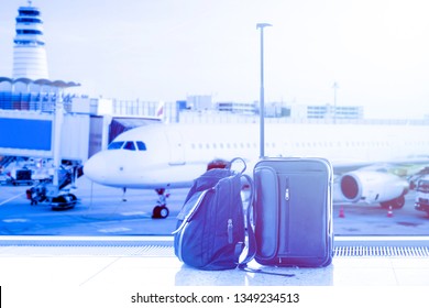 Business man suitcase and bag against air plane in the background in airport terminal during sunset. Concept of business trip and travel. Blue toned - Shutterstock ID 1349234513
