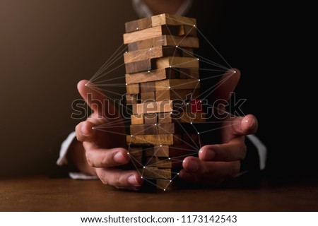 business man try to build wood block on wooden table and black background business organization startup concept