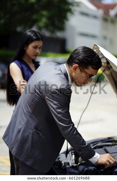 the
business man try to fixed the broken car on the way
