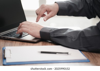 Business Man Typing On Laptop Computer Working In Office And White Paper Clip Board File Pen On The Table