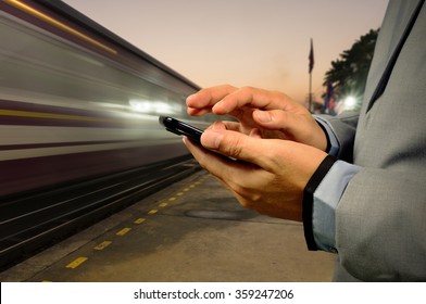 Business Man Use Mobile Phone In Railway Station At Dawn With High Speed Running Train