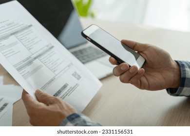 business man use phone to scan barcode or QR codes to pay credit card bill after receiving document invoice online. payment, receive, paying electricity, digital payments without money, technology