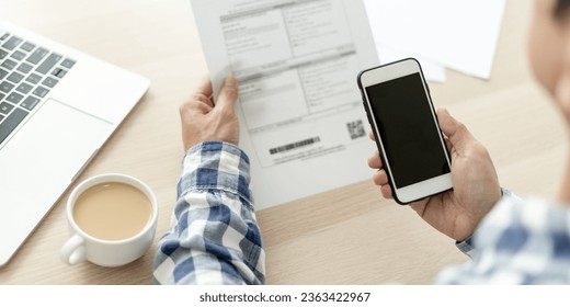 business man use phone to scan barcode or QR codes to pay credit card bill after receiving document invoice online. payment, receive, paying electricity, digital payments without money, technology
