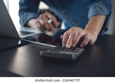 Business Man Using Calculator To Calculate Financial Data, E-document On Digital Tablet And Working On Laptop Computer At Office, Close Up