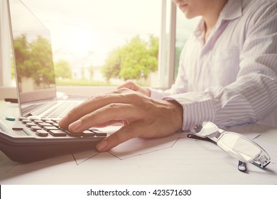 Business Man Using A Calculator To Calculate The Numbers In A Home Office