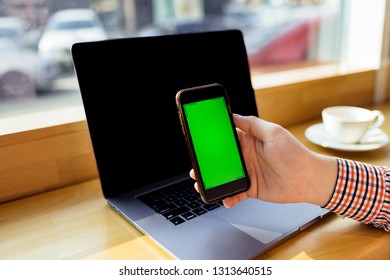 Business man using laptop computer and holding a smart phone.