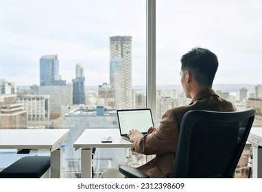 Business man using laptop in modern office city view sitting at desk. Businessman working computer with white blank mock up screen display for business websites or services ads. Over shoulder view. - Powered by Shutterstock