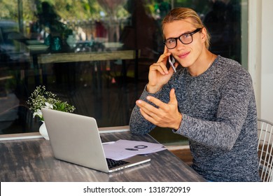 business man using laptop or netbook computer while seated at a cafe table outdoors talking on the phone.remote work - Shutterstock ID 1318720919