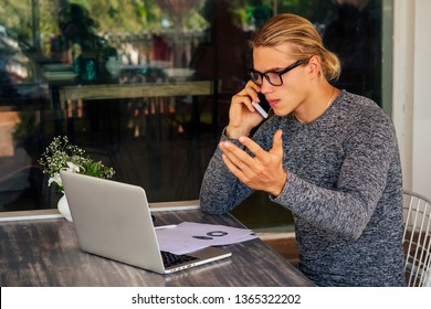 business man using laptop or netbook computer while seated at a cafe table outdoors talking on the phone.remote work - Shutterstock ID 1365322202