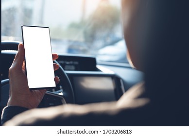 Business Man Using Mobile Smart Phone, Checking Address Location Via Navigator Application, Driving A Car. Driver Hand Holding And Looking At Cellphone Inside A Car, White Screen Mockup