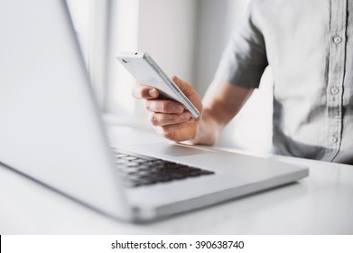 Business man using mobile smart phone at office desk. Young man student using laptop at home. Internet marketing, finance, business, home work, online learning, studying concept. Distance education