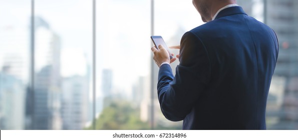 Business man using smart phone on window with city building background and copy space. - Shutterstock ID 672314896