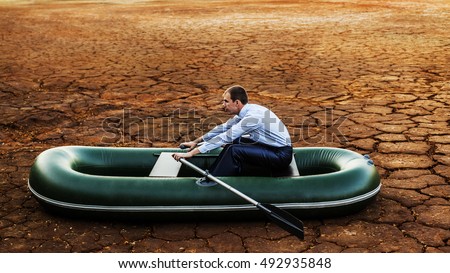 Business man will rows home for shore in paddle powered row boat businessman in boat rocks looks bright future symbol crisis stagnation losses braking environmental disaster water scarcity drought