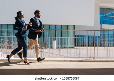 Business man and woman running outdoors. Business people wearing formal clothes with building in background. Business competition concept. Side view. - Powered by Shutterstock