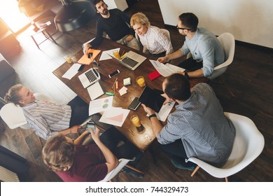 Business Man And Woman Sitting Around Table At Office And Working With Laptops And Tablet. Coworking People Discussing New Plan Development Bussines