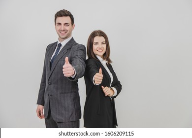 Business Man And Woman Standing Back To Back, Giving Thumbs Up, Smiling.